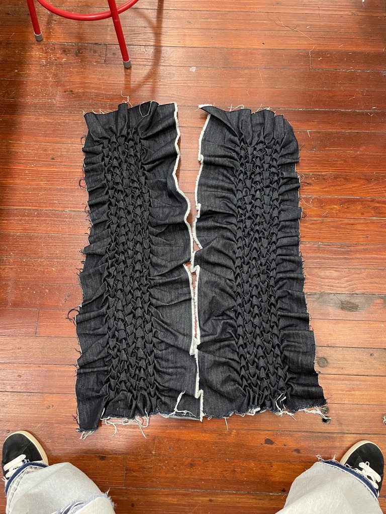 Two dark denim panels covered in Canadian smocking before assembly